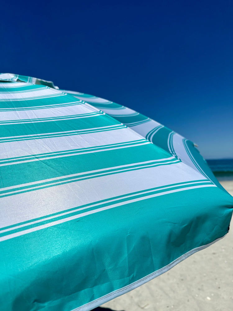 Daytripper 210cm beach umbrella in turquoise and white stripes on sandy beach under clear blue sky