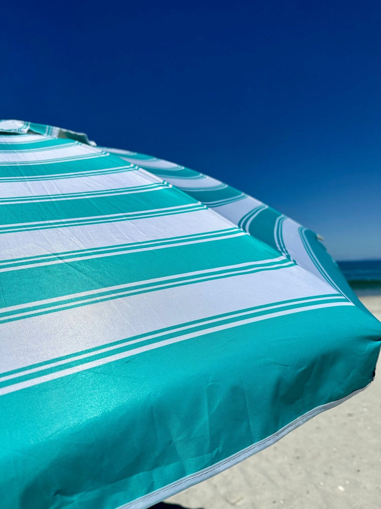 Daytripper 210cm beach umbrella turquoise and white stripes on sandy beach under clear blue sky