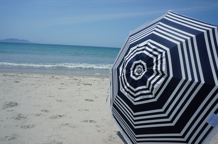 Hollie & Harrie Classic Fringe 210cm blue and white striped cotton beach umbrella on sandy shore