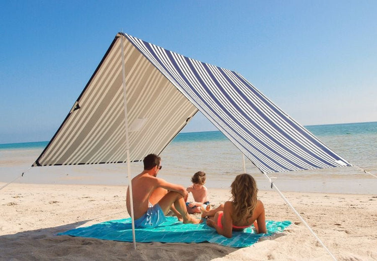 Lovin Summer Sombrilla shade tent with blue and white stripes on a beach providing UPF 40 sun protection for family relaxation