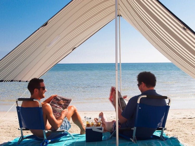 Lovin Summer beach shade tent with UPF 40 cooling two men on sand under striped cotton canopy