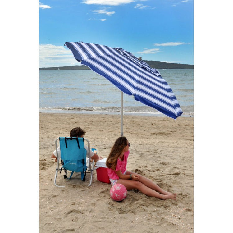 Compact beach umbrella with nautical stripes providing shade on the sandy beach.