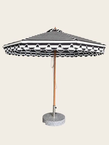 A grey and white striped patio umbrella with a scalloped edge, a wooden pole, and a round concrete base on a white background.