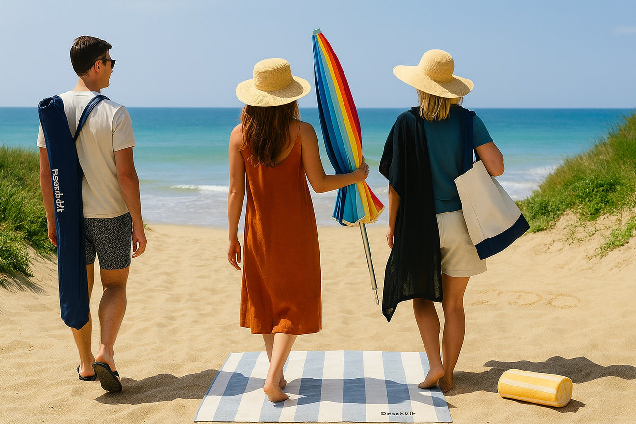 Three people with beach essentials walking on a sandy beach.